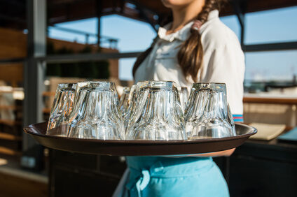 Waitress is carrying tray with glasses